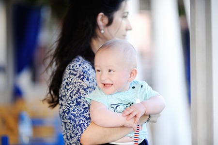 Young mother holding her smiling baby boy. Parenthood concept. Mommy and son