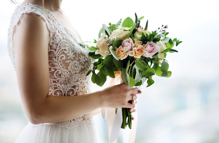 Bride holding stylish wedding flowers. Elegance rustic style pastel colors bouquet in woman handsの写真素材