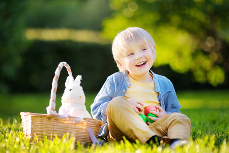 Little boy hunting for easter egg in spring garden on Easter day. Cute little child with traditional bunny celebrating feastの写真素材