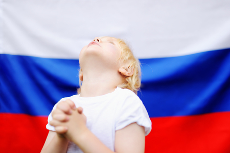 Portrait of emotional little boy with russian flag on background. Fans child supporting and cheering their national team at the sporting gamesの写真素材
