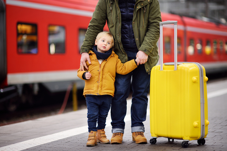 Little boy and his father waiting express train on railway station platform. Travel, tourism, winter vacation and family concept. Man and his son together.の写真素材