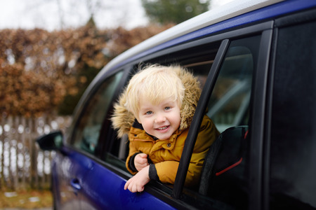Cute little boy ready for a roadtrip or travel. Family car travel with kids. Child transportation safetyの写真素材