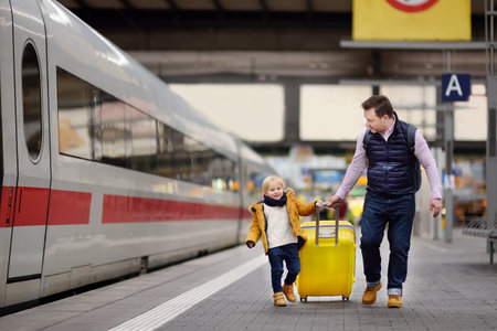 Cute little boy and his father waiting express train on railway station platform. Travel, tourism, winter vacation and family conceptのeditorial素材