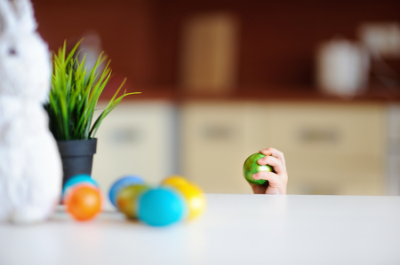 Cute toddler child hunting for easter egg on Easter day. Little boy celebrate Easter at home.