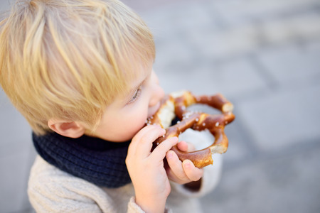 Little tourist eating traditional bavarian bread called pretzel in Munich, Germany. National cuisine conceptの写真素材