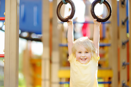 Little boy having fun on outdoor playground. Summer active sport leisure for kids. Kindergarten or school yard. Toddler child activityの写真素材