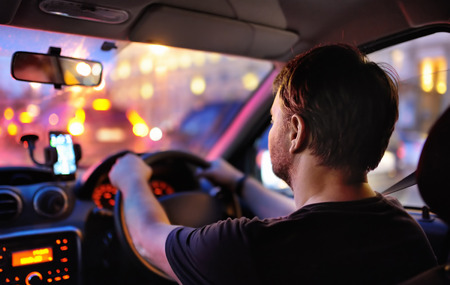 Male driver ride a car during evening traffic jam. Drive in the night city. Inside view.の写真素材