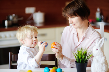 Beautiful woman and her cute son or grandson playing with easter egg on Easter day. Little boy with family celebrate Easter at home. Holiday activity with little kid and family time conceptの写真素材