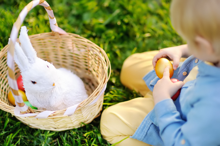 Close-up photo of little boy hunting for easter egg in spring park on Easter day. Cute little child...
