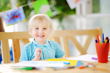 Cute little boy drawing and painting with colorful markers pens at kindergarten. Creative kid painting at playschool. Development toys for preschooler childrenの写真素材