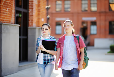 Young happy students with books and notes outdoors. Smart young guy and girl in University campus. Learning and education for young people.の写真素材