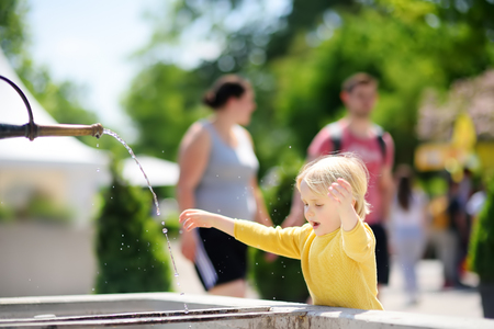 Little blonde hair boy playing with city fountain on sunny summer day. Active outdoor leisure for kids. Preschooler child having fun with water. Rheinfall, Switzerland, Europeの写真素材