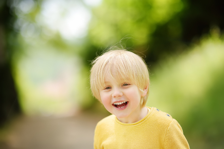 Cheerful little boy enjoying warm summer day. Active child playing in park. Freedom, rest and childhood concept. Portrait of happy kid outdoors with copy spaceの写真素材