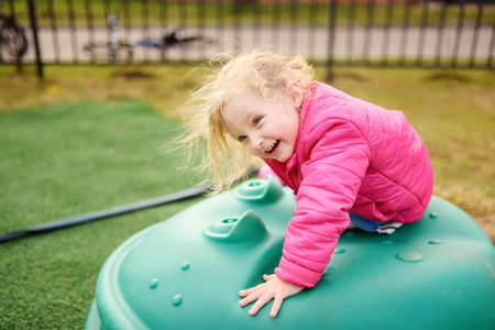 Cute little girl having fun on outdoor playground. Spring/summer/autumn active sport leisure for kidsの写真素材