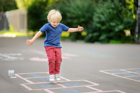 Child playing hopscotch on playground outdoors on a sunny day. Activities for preschooler kids.の写真素材