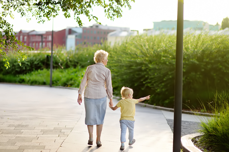 Beautiful granny and her little grandchild walking together in park. Grandmother and grandson holding hands. Family timeの写真素材