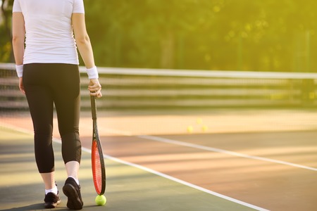 Young female tennis player with tennis ball and racket preparing to serve. Girl on tennis courtの写真素材
