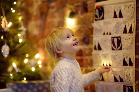 Happy little boy takes sweet from advent calendar on Christmas eve. Traditional christmas calendar for kidsの写真素材