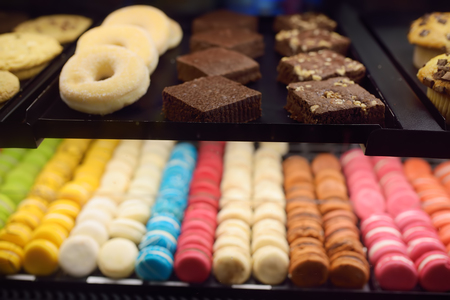 Macaroon, donuts, biscuits, muffins in the window of a cafe or store. Sweets.の写真素材