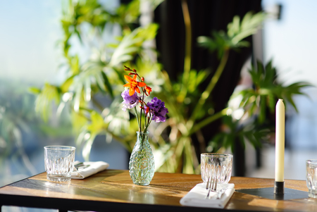 Table in a cafe or restaurant with flowers in a vase and a candle. Catering.の写真素材