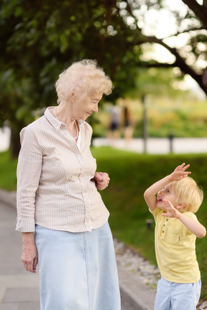 Beautiful granny and her little grandchild together walking. Grandma and grandson talking. Family communication concepts. Active longevity concepts.の写真素材