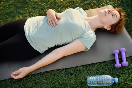 Mature woman lying relaxing after exercise with dumbbells. Healthy lifestyle.の写真素材