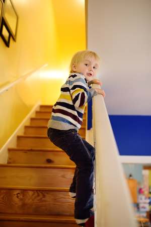 Cute little boy in striped jumper on the stairs at home. ?hildren's gameの写真素材