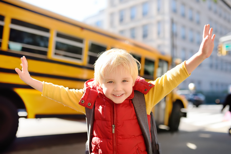 Pupil with schoolbag with yellow school bus on background. Back to school.の写真素材