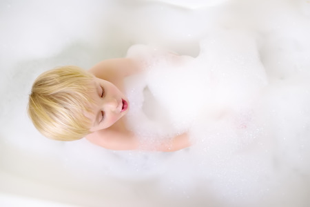 Cute little boy taking a foam bubble bath view from above. Hygiene for little childの写真素材