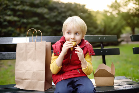 Little boy is eating his lunch after kindergarten. Street food for childs. Healthy snacks for kids.の写真素材