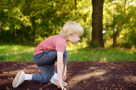 Little boy sportsman getting ready to run a distance at the school stadium. Kids sports.の写真素材