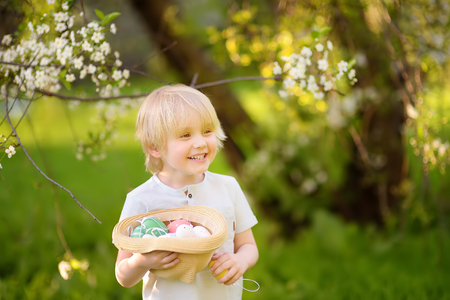 Charming little boy hunting for easter egg in spring park on Easter day.Traditional easter festival...