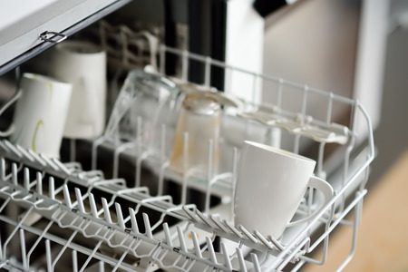 Open dishwasher with dirty crockery in the modern kitchen. Close-up. Domestic appliances for help...