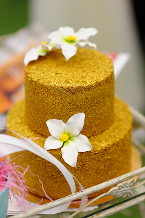 Gold wedding cake decorated with white sugar flowers. Sweet table on wedding partyの写真素材