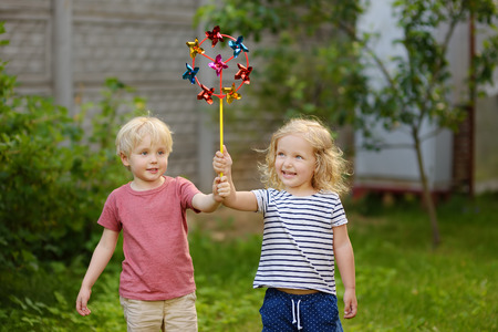 Little boy and girl having fun during walk. Happy child with pinwheel. Preschoolers or toddlers birthday party in summer park.の写真素材