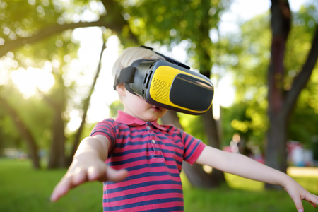 Little boy using virtual reality headset outdoor. VR, VR glasses, augmented reality experience. Kids and modern technology, innovation.の写真素材