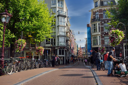 AMSTERDAM, NETHERLANDS - SEPTEMBER 17, 2018: Traditional view of street of Amsterdam with crowd of people, parking bicycles, shops, cafe, cofeshops. Sightseeing of Dutch. Tourism and travel in Hollandのeditorial素材