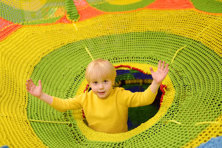 Happy little boy having fun in amusement in play center. Child playing on indoor playground. Active birthday party for preschooler kids.の写真素材