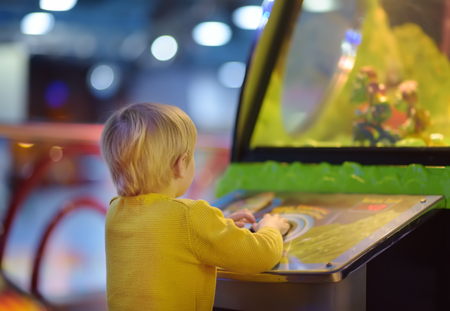 Little boy having fun in amusement in play center. Kid playing on slot machine in Arcade centre. Entertainment industry for childs.の写真素材