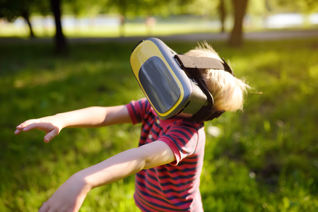 Little boy using virtual reality headset outdoor. VR, VR glasses, augmented reality experience. Kids and modern technology, innovation.の写真素材