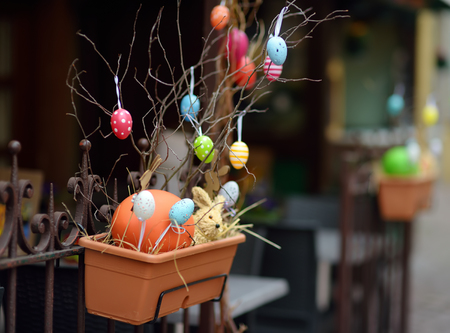 Easter decorations on the street of small town in France. Easter painted eggs hanging on a branch of...