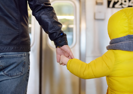 Mature man and his little son looks out the window of the car in the subway in new York. Transport...