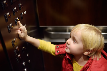 Lttle boy pressing button of lobby in elevator. Independent child.の写真素材