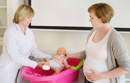 Pregnant woman on lesson courses for expectant mothers. Medical insurance childbearing. Family doctor for gestation. Maternity leave. Pediatrics. Preparing for motherhood.の写真素材