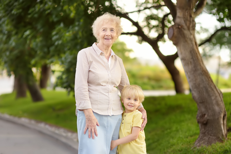 Beautiful granny and her little grandchild walking together in park. Grandma and grandsonの写真素材