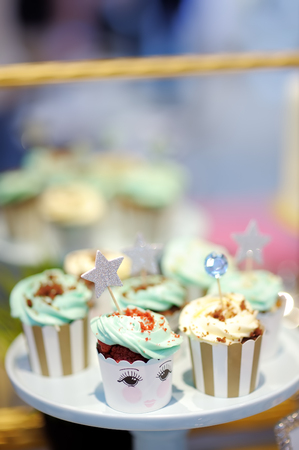Delicious colorful wedding cupcakes with flower and stars and beautiful iced cake. Beautiful delicious sweet dessert on blurred backgroundの写真素材