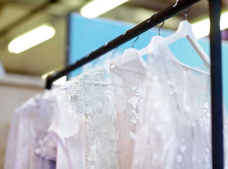 Few elegant wedding, bridesmaid ,evening, ball gown or prom dresses on a hanger in a bridal shop. Fashion for beautiful brides.の写真素材