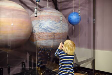 Little caucasian boy is looking an exposition in a scientific museum. Models of planets of the solar system. Education and entertainment for children. Activities for family with preschooler kids.の写真素材