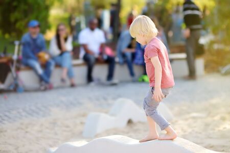 Little boy having fun on playground of public park at sunny summer day. Active summer leisure for kids.の写真素材