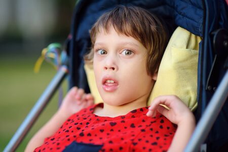 Portrait of a cute little disabled girl in a wheelchair. Child cerebral palsy. Inclusion. Family with disabled kid.の写真素材